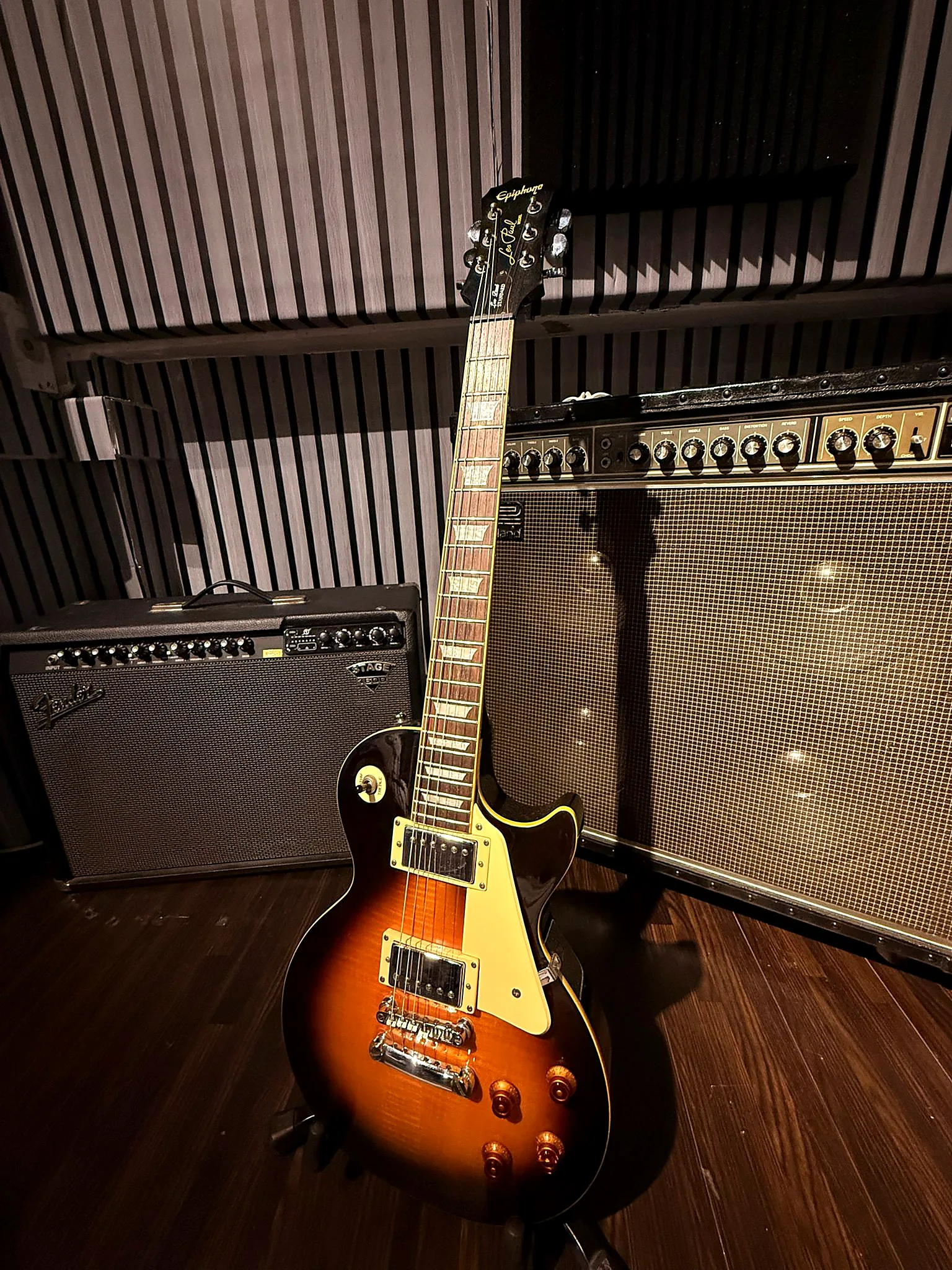 Electric guitar on a stand in front of the amp wall